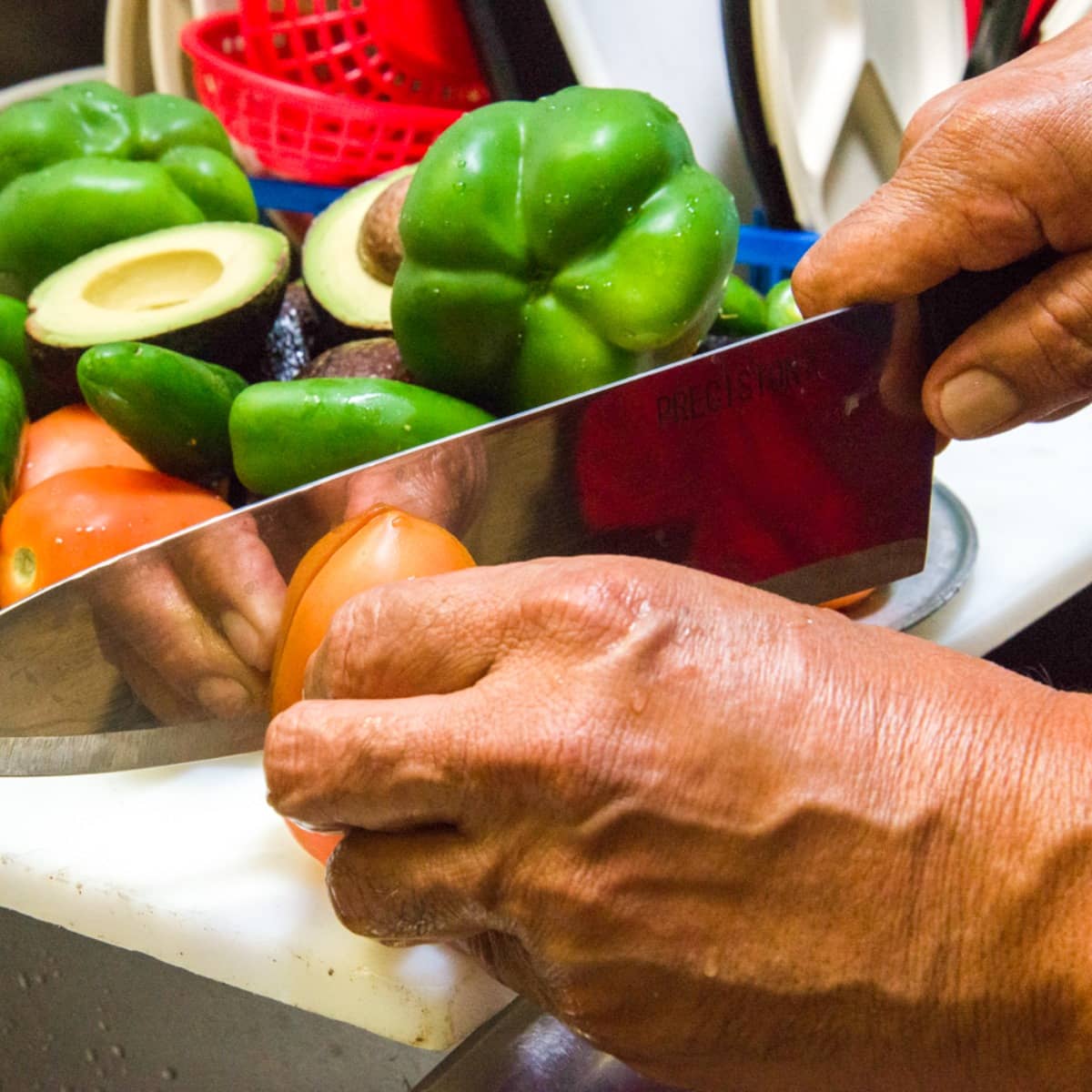 A cook hand-cutting fresh vegetables in the El Patron kitchen